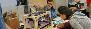 A group of people working on a 3d printer.